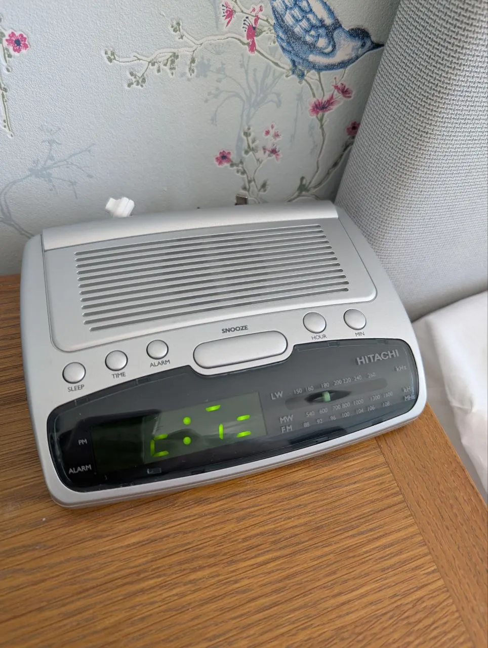A digital alarm clock radio on a bedside cabinet
